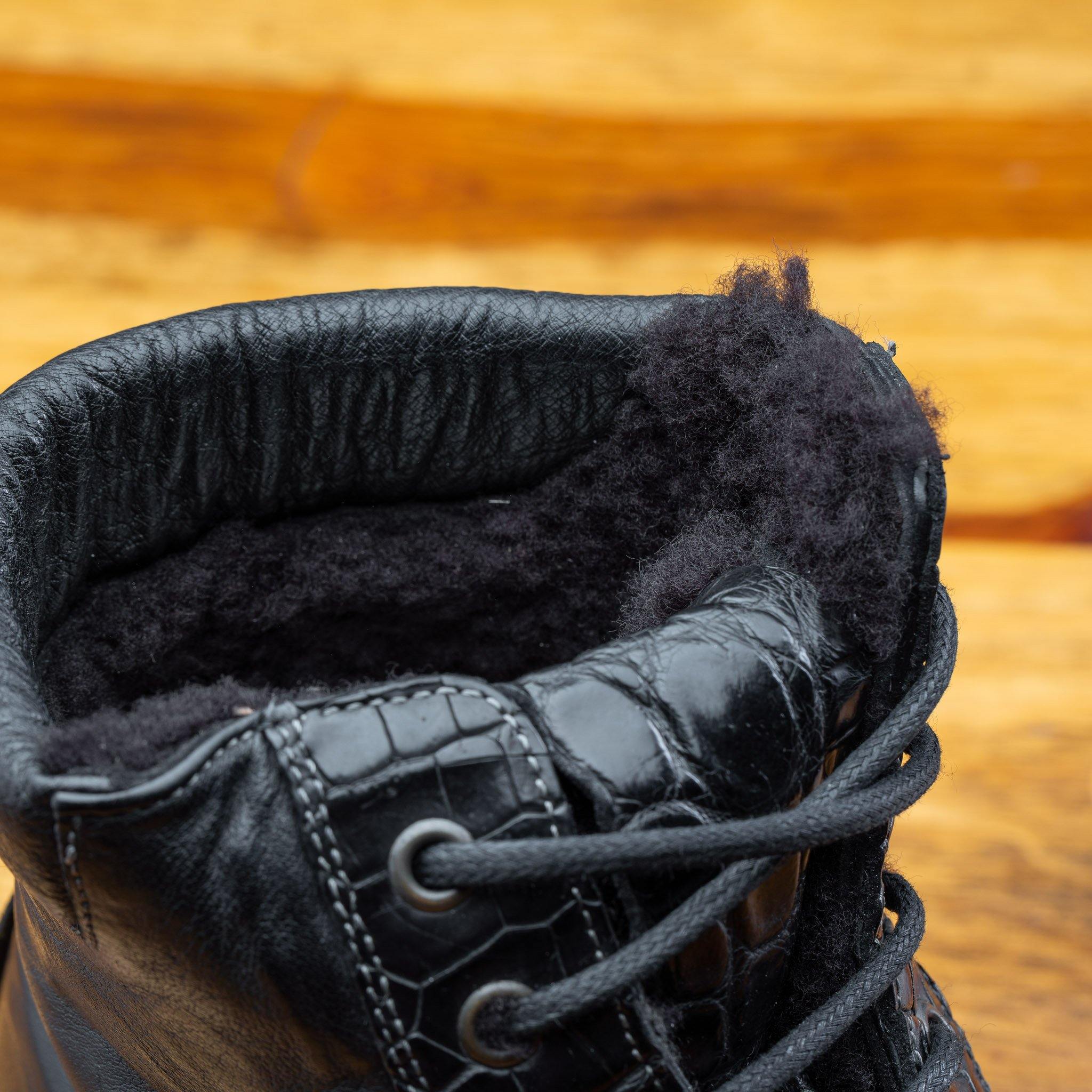 Close view of Black leather boots on a wooden surface