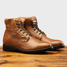 Pair of brick leather boots on a wooden surface.