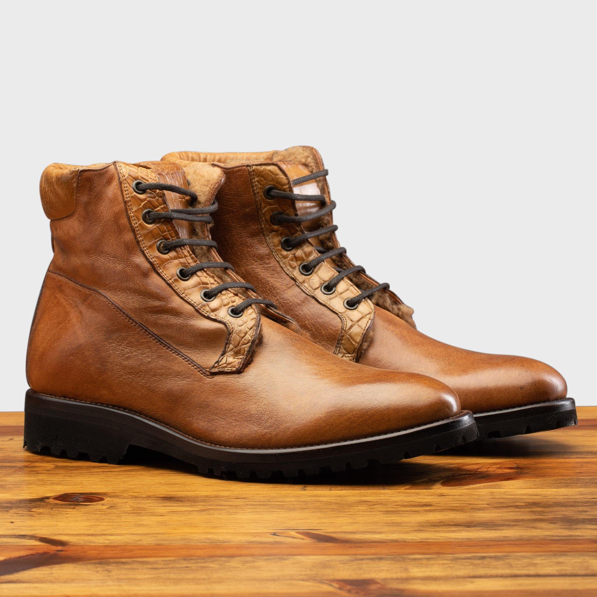 Pair of brick leather boots on a wooden surface.
