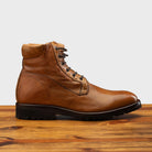 Brick leather boot on a wooden surface with a light gray background