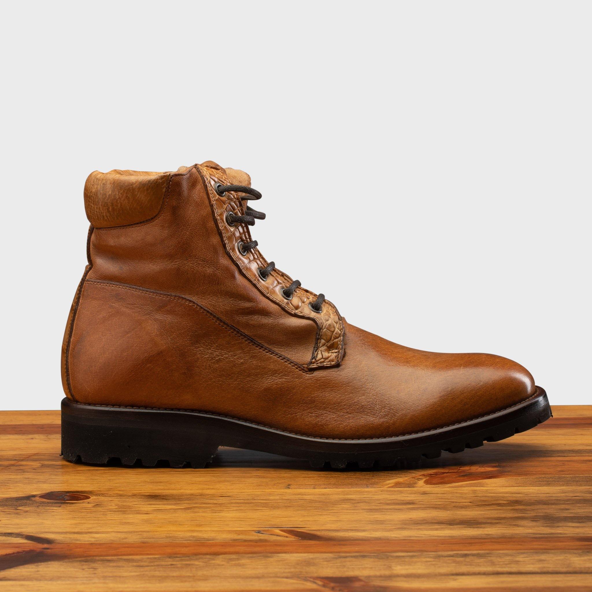 Brick leather boot on a wooden surface with a light gray background