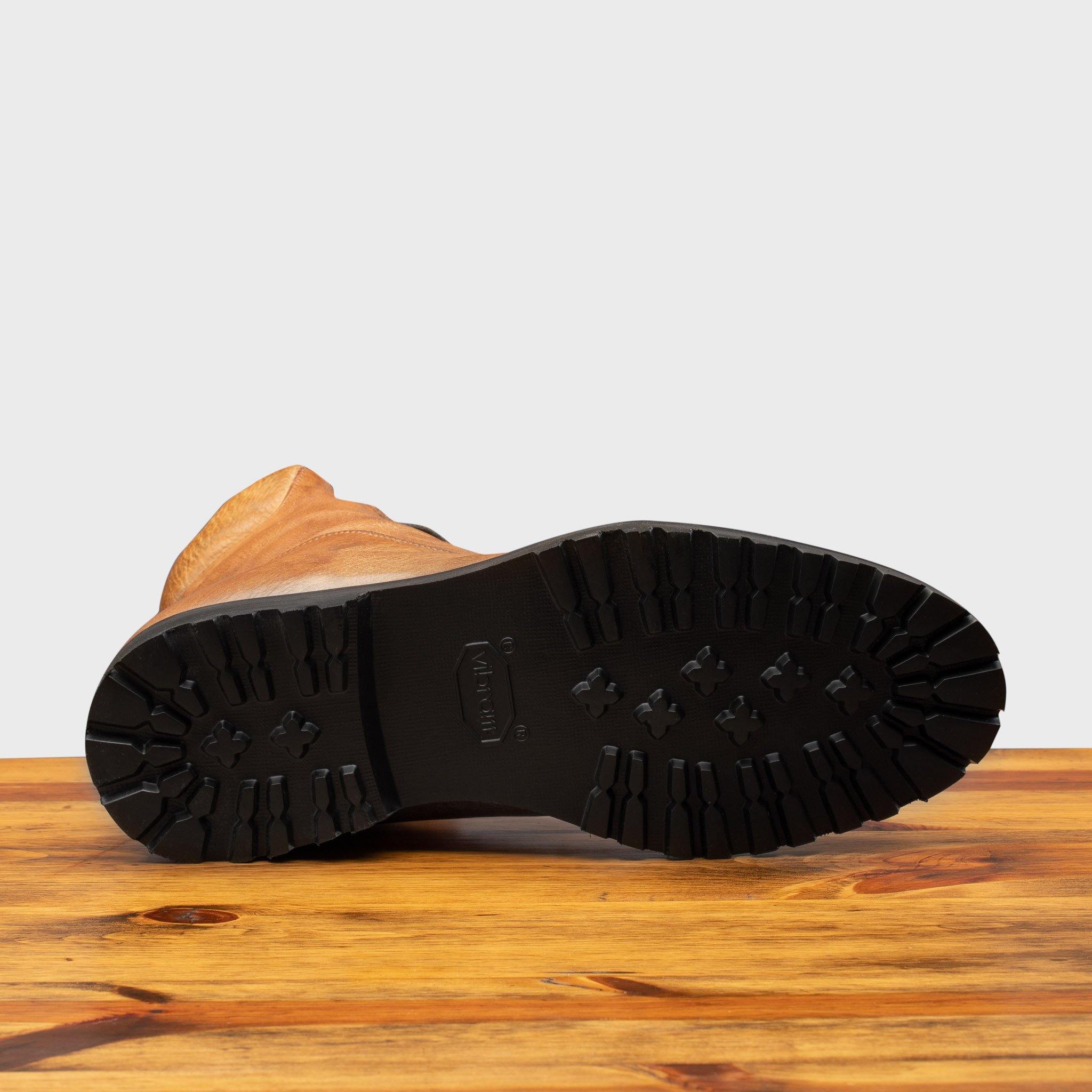 Outsole of Brick leather boot on a wooden surface with a light gray background