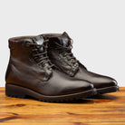 Darl Brown leather boot on a wooden surface with a light gray background