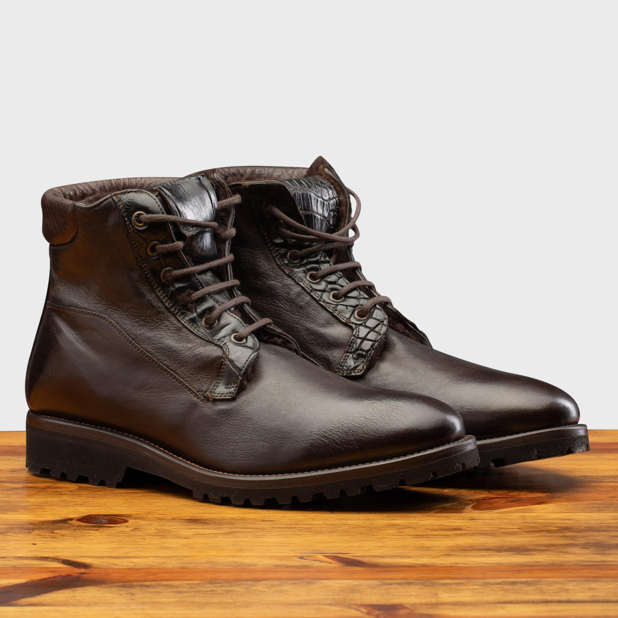Darl Brown leather boot on a wooden surface with a light gray background