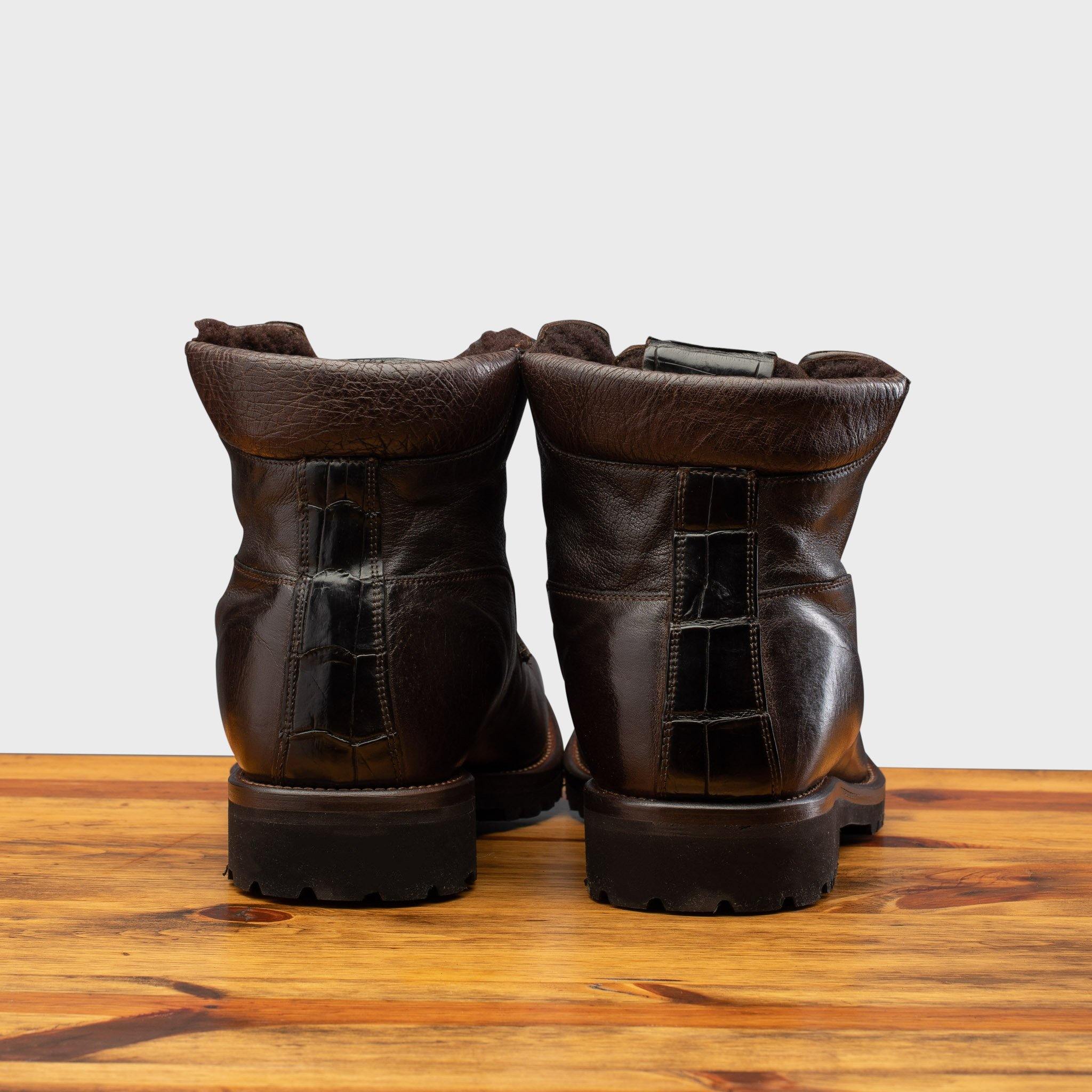 Back view of Dark  Brown leather boot on a wooden surface with a light gray background