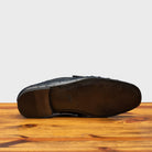 Outsole of Blue leather loafer on a wooden surface with a light gray background