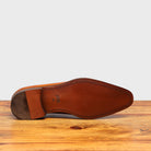 Outsole of Caramel leather dress shoe on a wooden surface with a light gray background