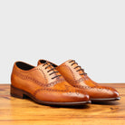Pair of Brown leather dress shoe on a wooden surface with a light gray background