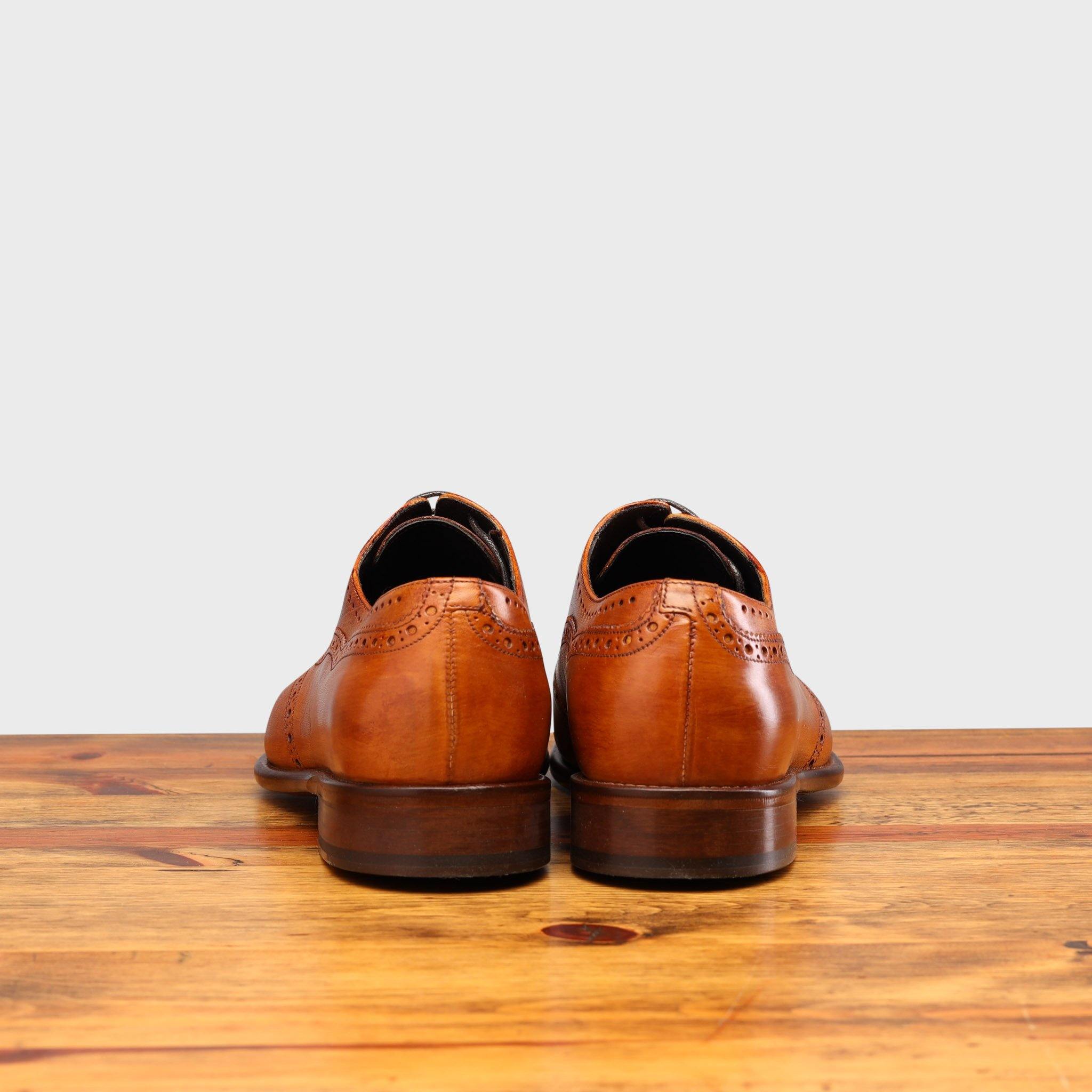 Back View of Brown leather dress shoe on a wooden surface with a light gray background
