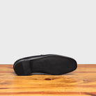 Outsole of Blue loafer shoe on a wooden surface with a light gray background