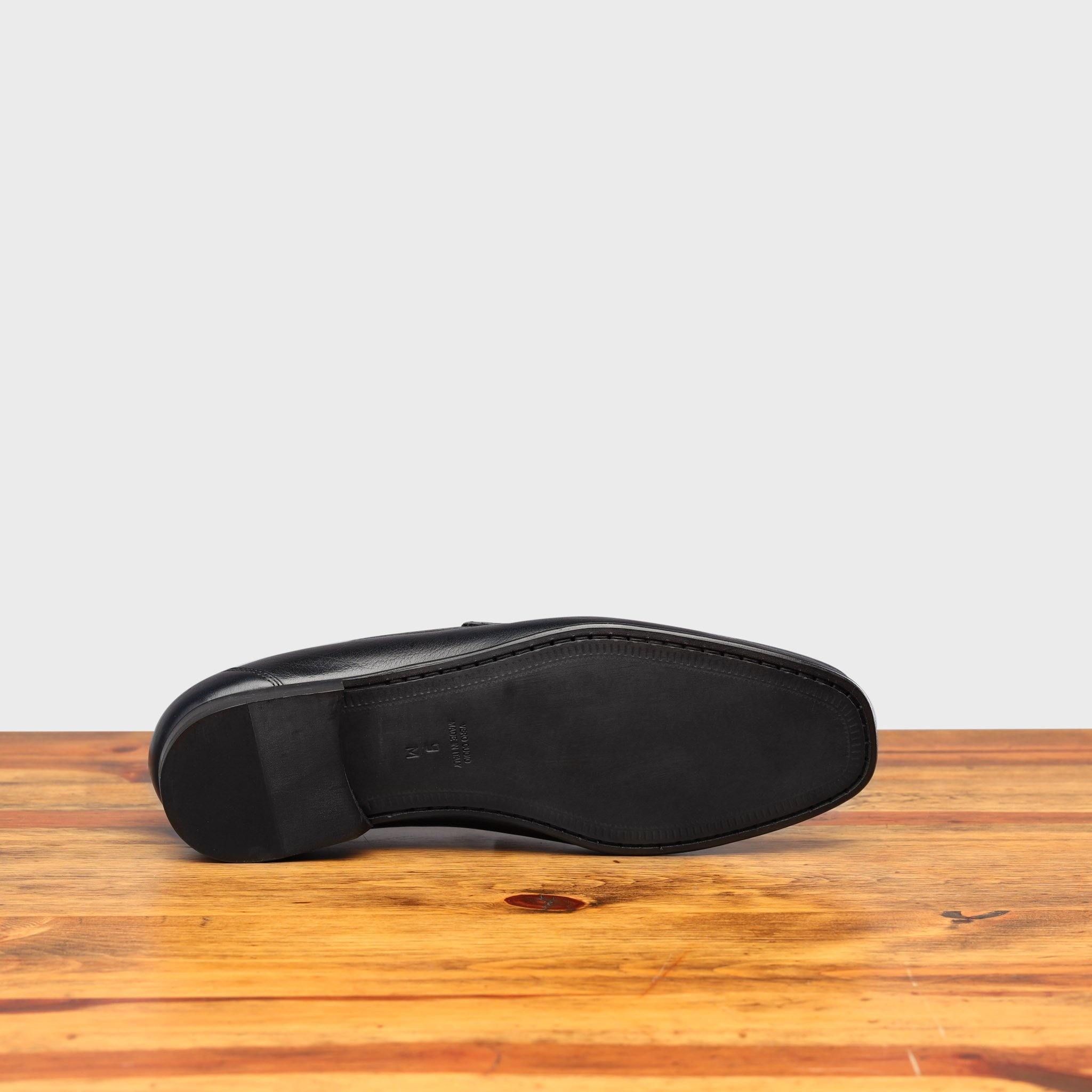 Outsole of Blue loafer shoe on a wooden surface with a light gray background