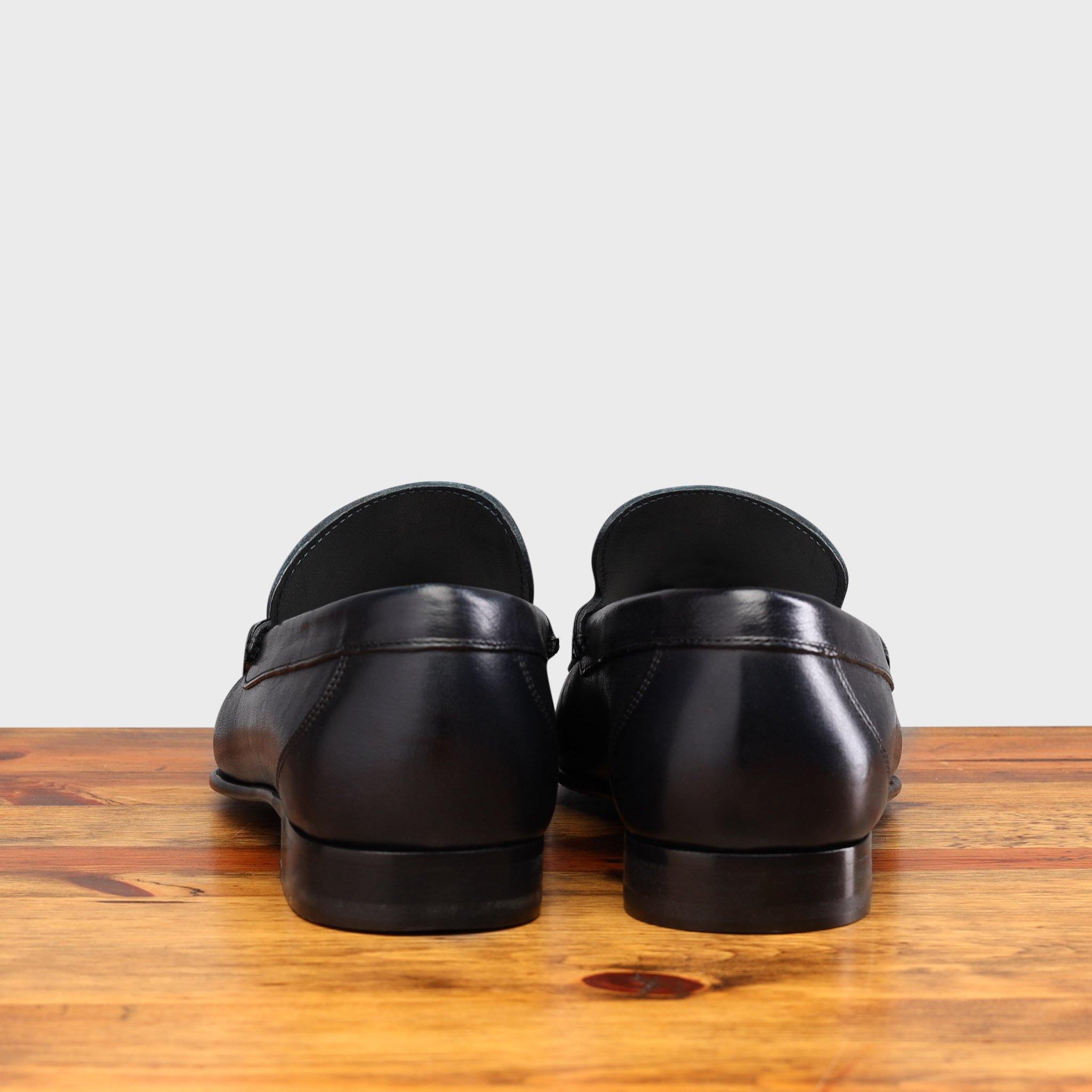 back view of Blue loafer shoe on a wooden surface with a light gray background