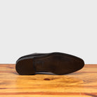 Outsole of Graphite leather dress shoe on a wooden surface with a light gray background