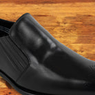 Black leather shoe on a wooden