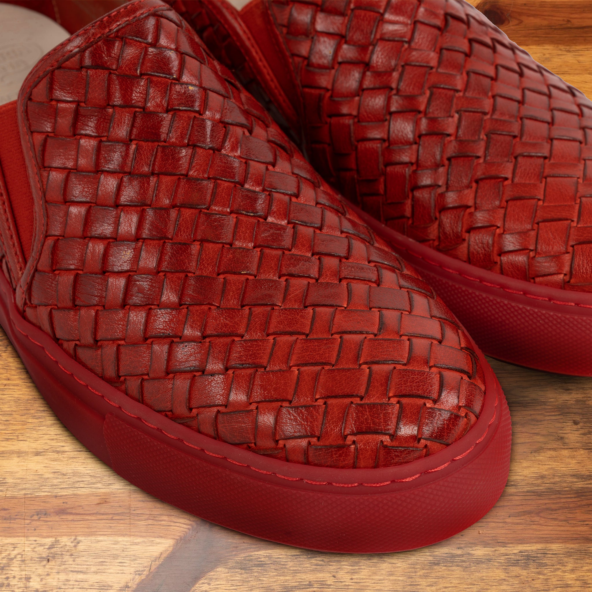 Red woven slip-on shoe on a wooden surface