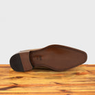 Outsole of Spice leather loafer on a wooden surface with a light gray background