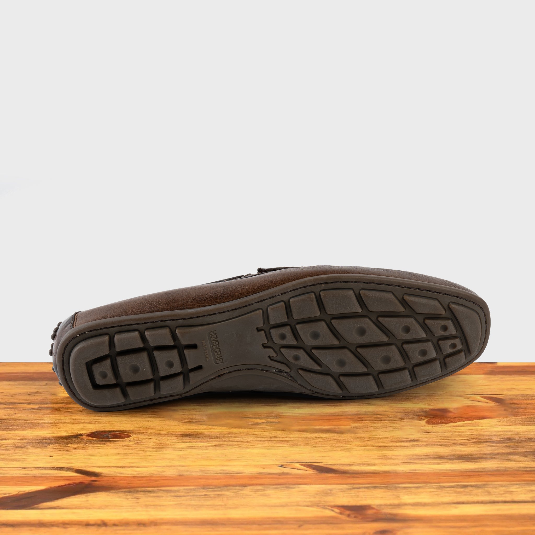 Outsole of Moor leather loafer on a wooden surface with a white background