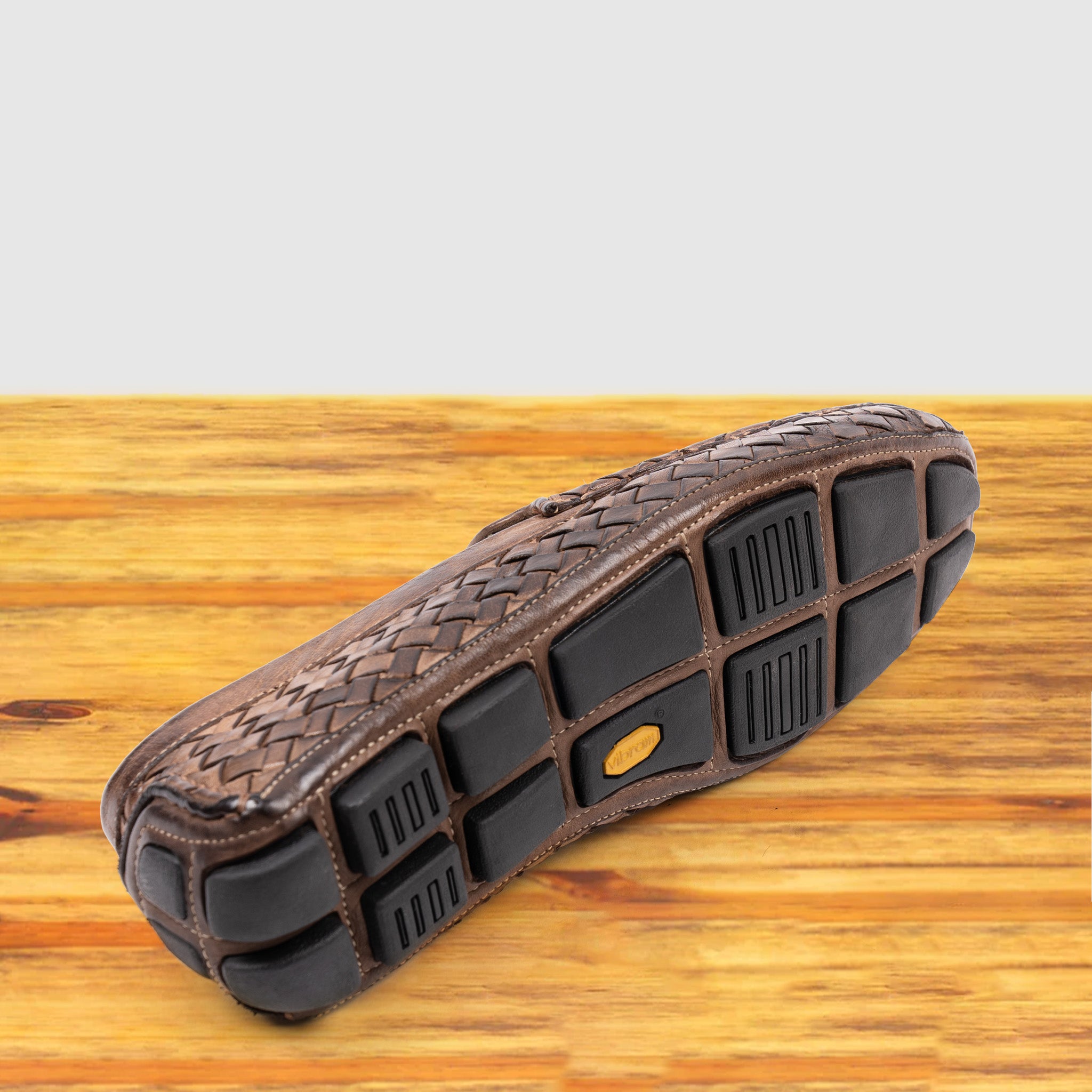 Outsole of Moor loafer shoe with woven pattern on a wooden surface