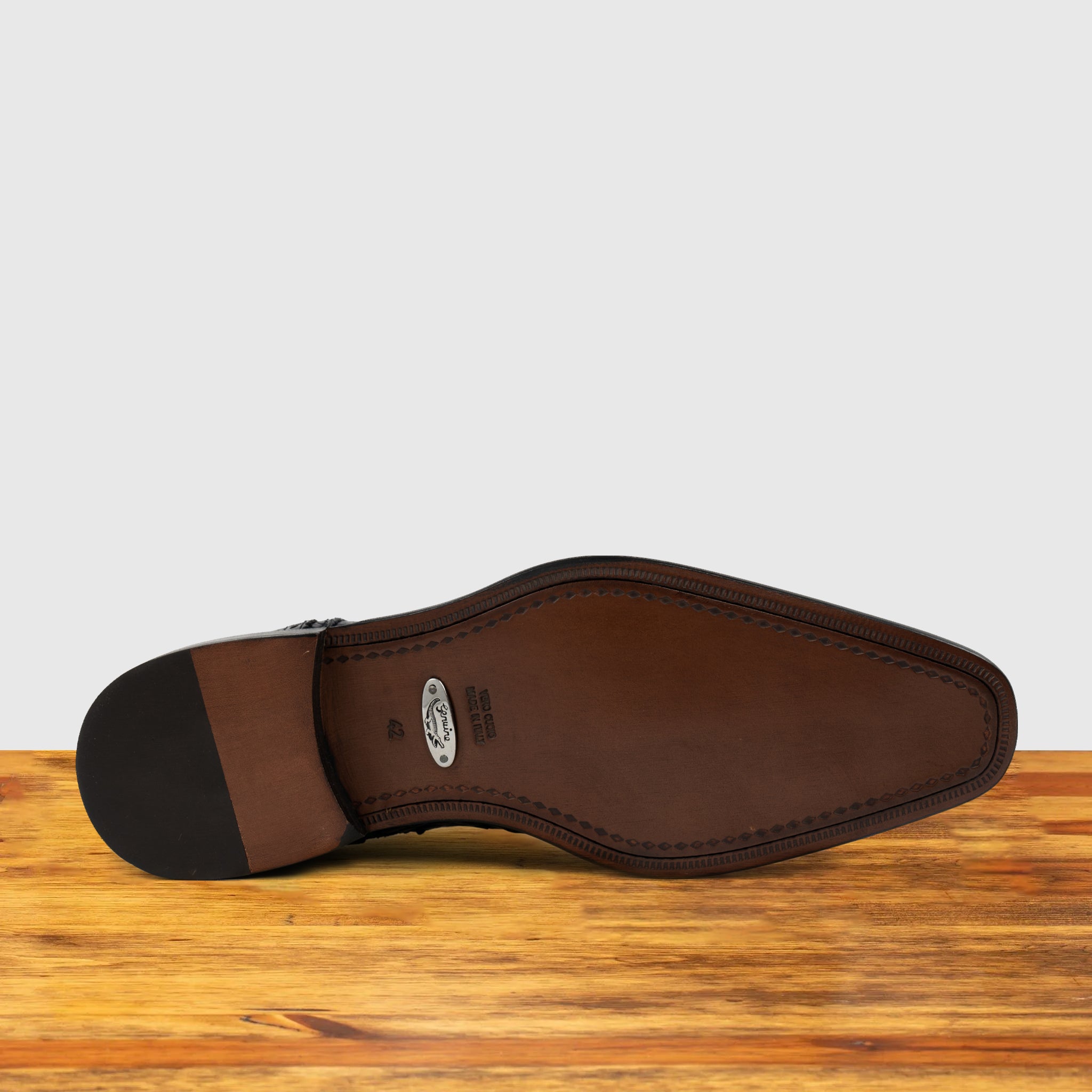 Outsole of Blue ostrich dress shoe with studded details on a wooden surface