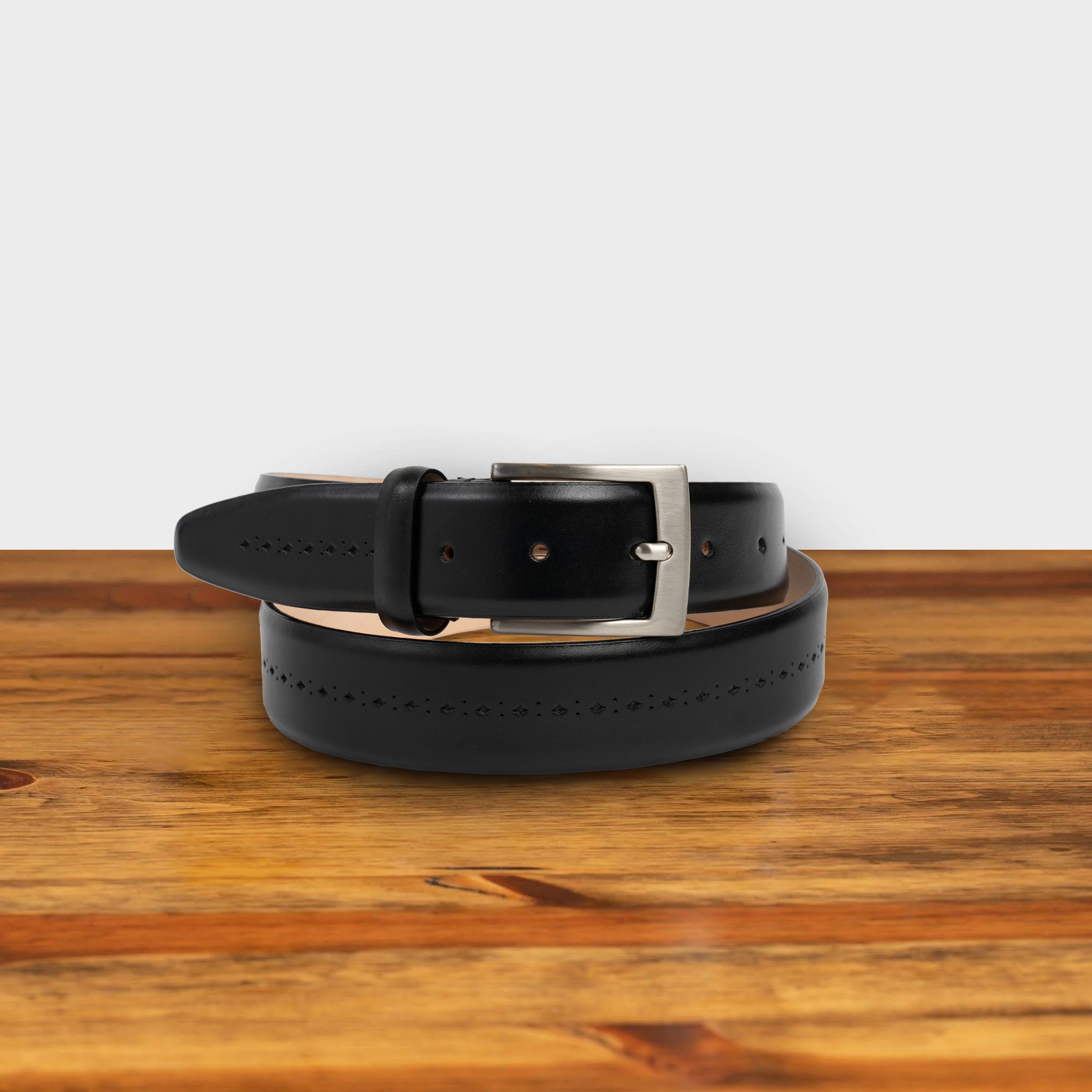 Black leather belt with a gold buckle on a wooden surface
