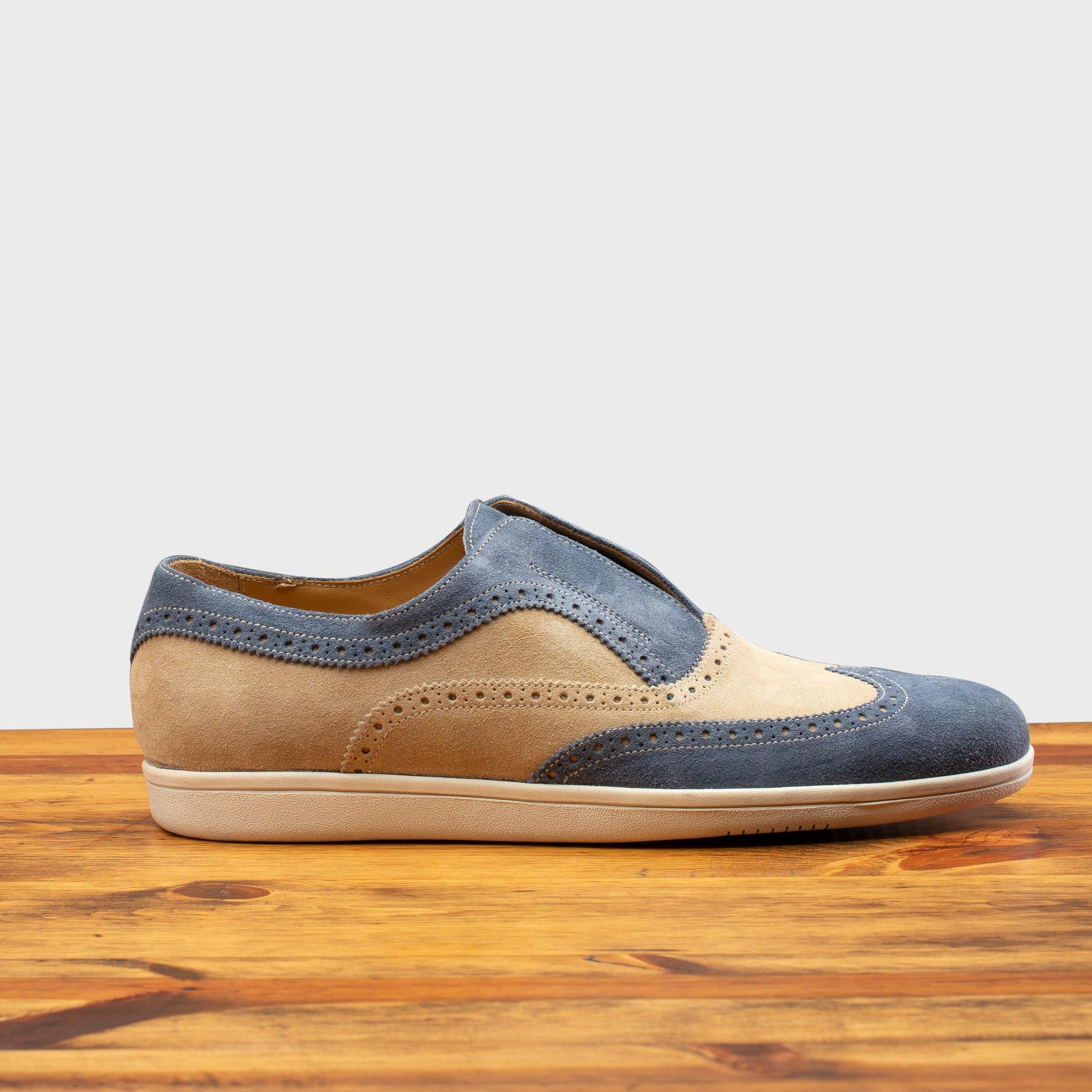 Two-tone shoe with beige and blue design on a wooden surface