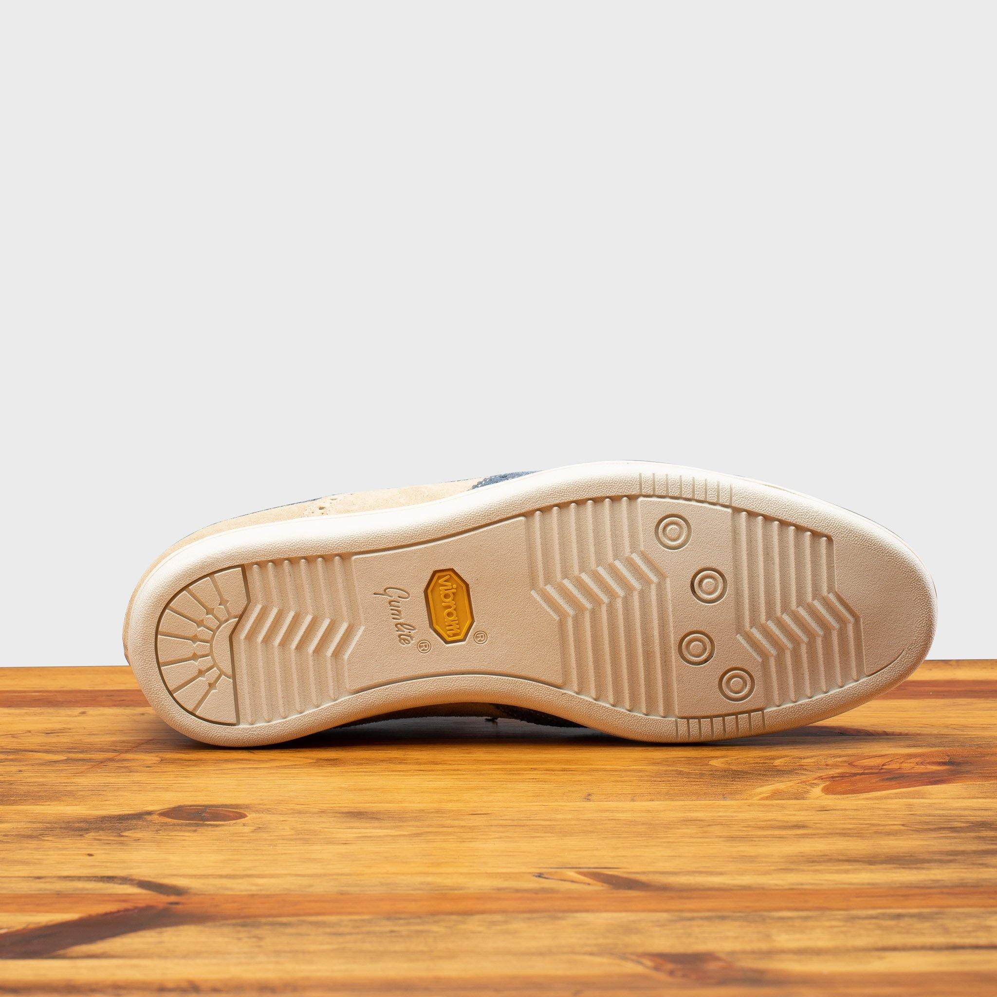 Outsole of Two-tone shoe with beige and blue design on a wooden surface