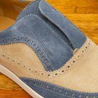 Close-up of Two-tone shoe with beige and blue design on a wooden surface