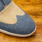 Close-up of Two-tone shoe with beige and blue design on a wooden surface