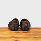 Back view of Dark brown crocodile-patterned loafer on a wooden surface with a light gray background