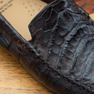 Close view of Dark brown crocodile-patterned loafer on a wooden surface