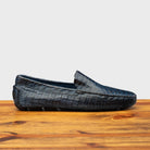 Denim crocodile-patterned loafer on a wooden surface with a light gray background
