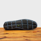 Outsole of Denim crocodile-patterned loafer on a wooden surface with a light gray background