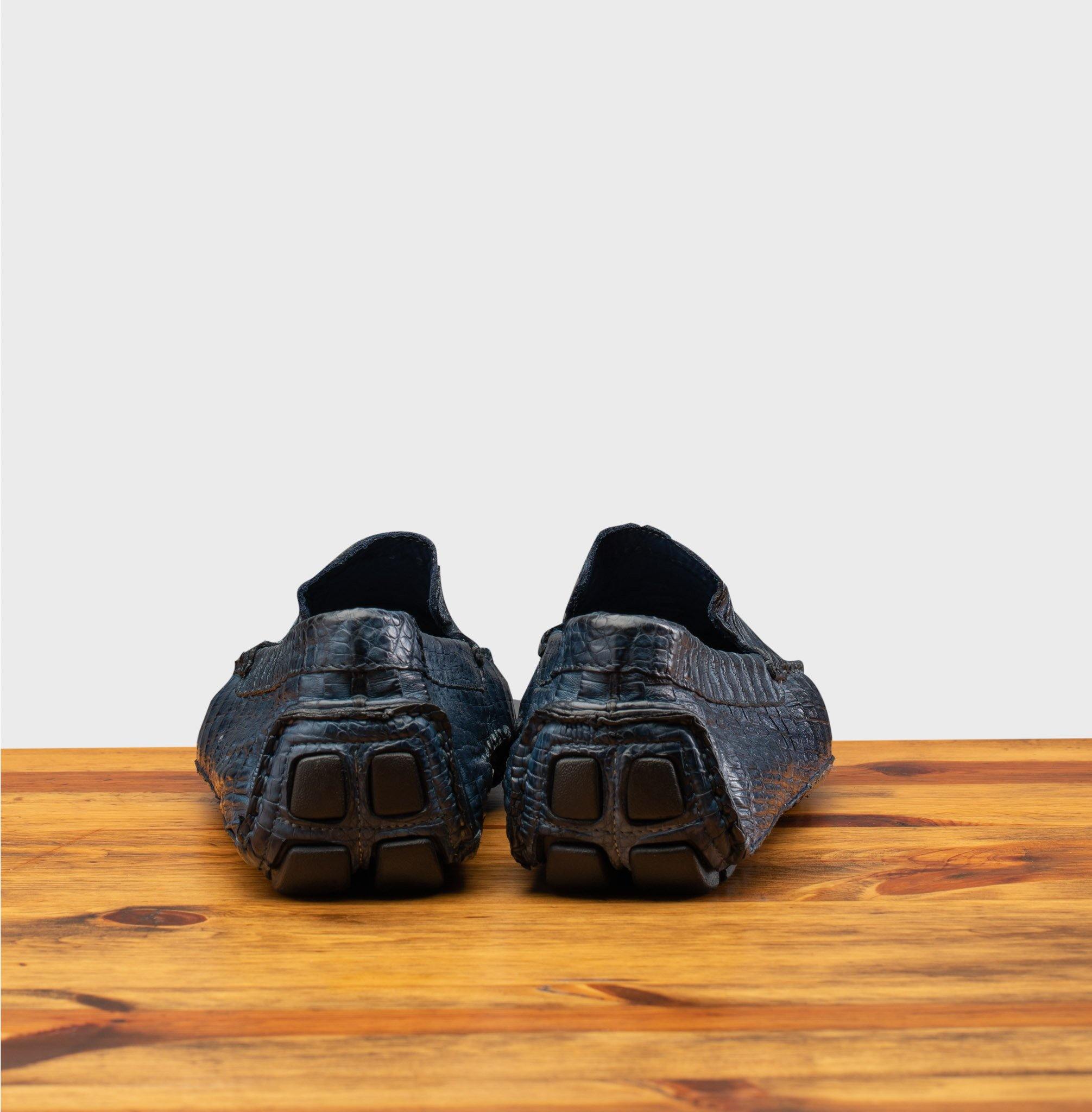 Back view of Denim crocodile-patterned loafer on a wooden surface with a light gray background