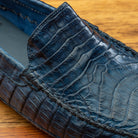 Close view of Denim crocodile-patterned loafer on a wooden surface