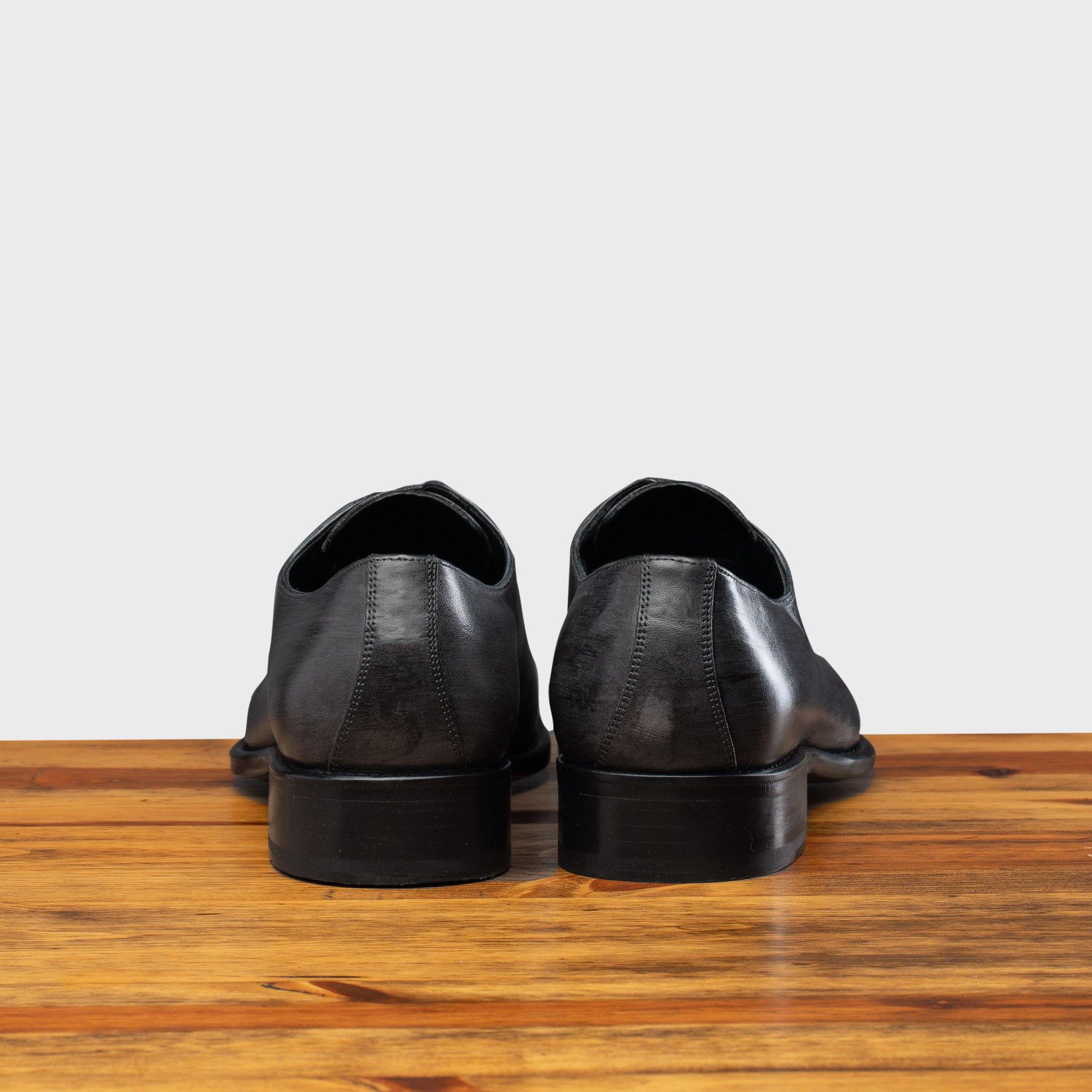 A Pair of Grey leather dress shoe on a wooden surface with a light gray background