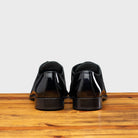 Back Side of Shiny blue dress shoe on a wooden surface with a light gray background