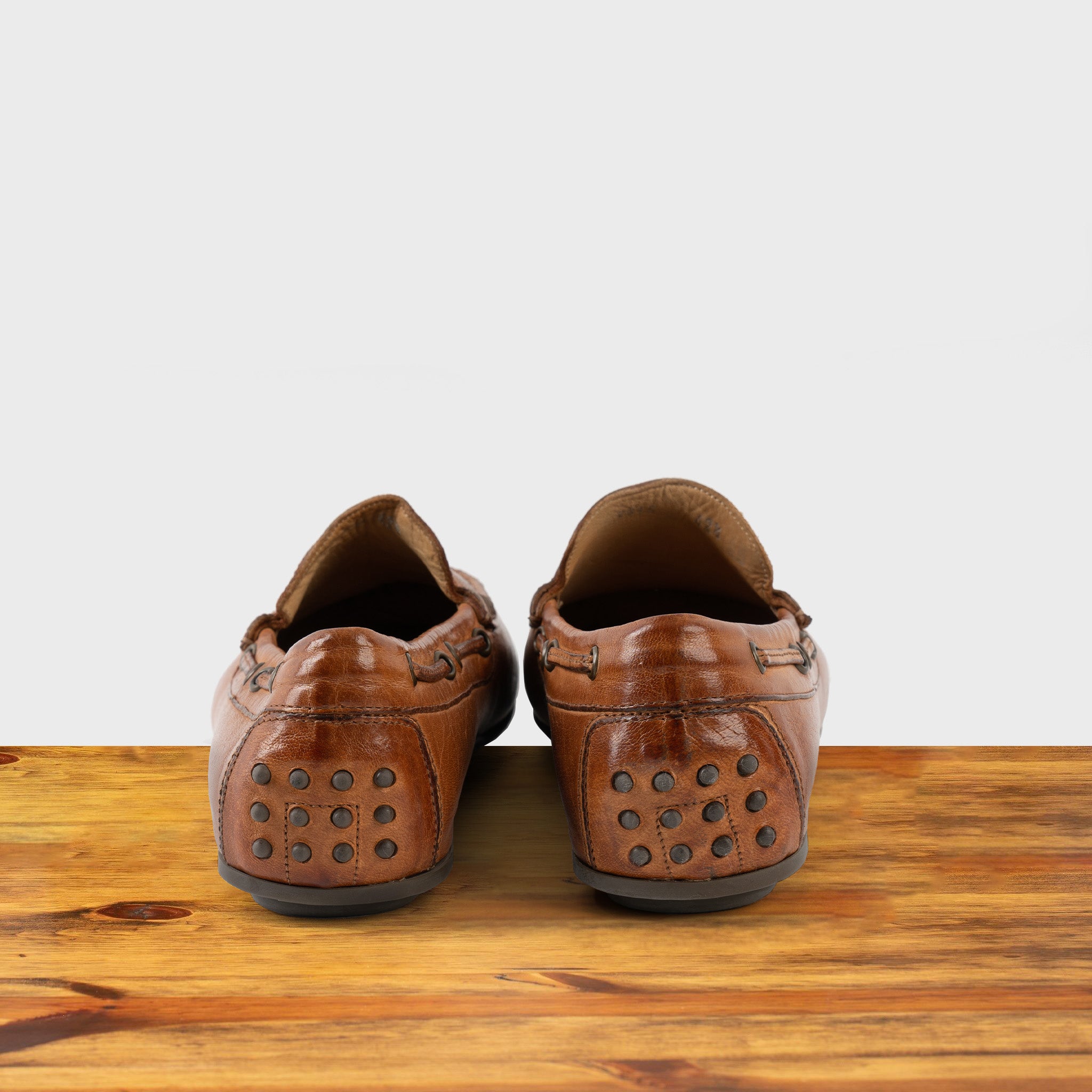 A Pair of Brick leather loafer on a wooden surface with a white background