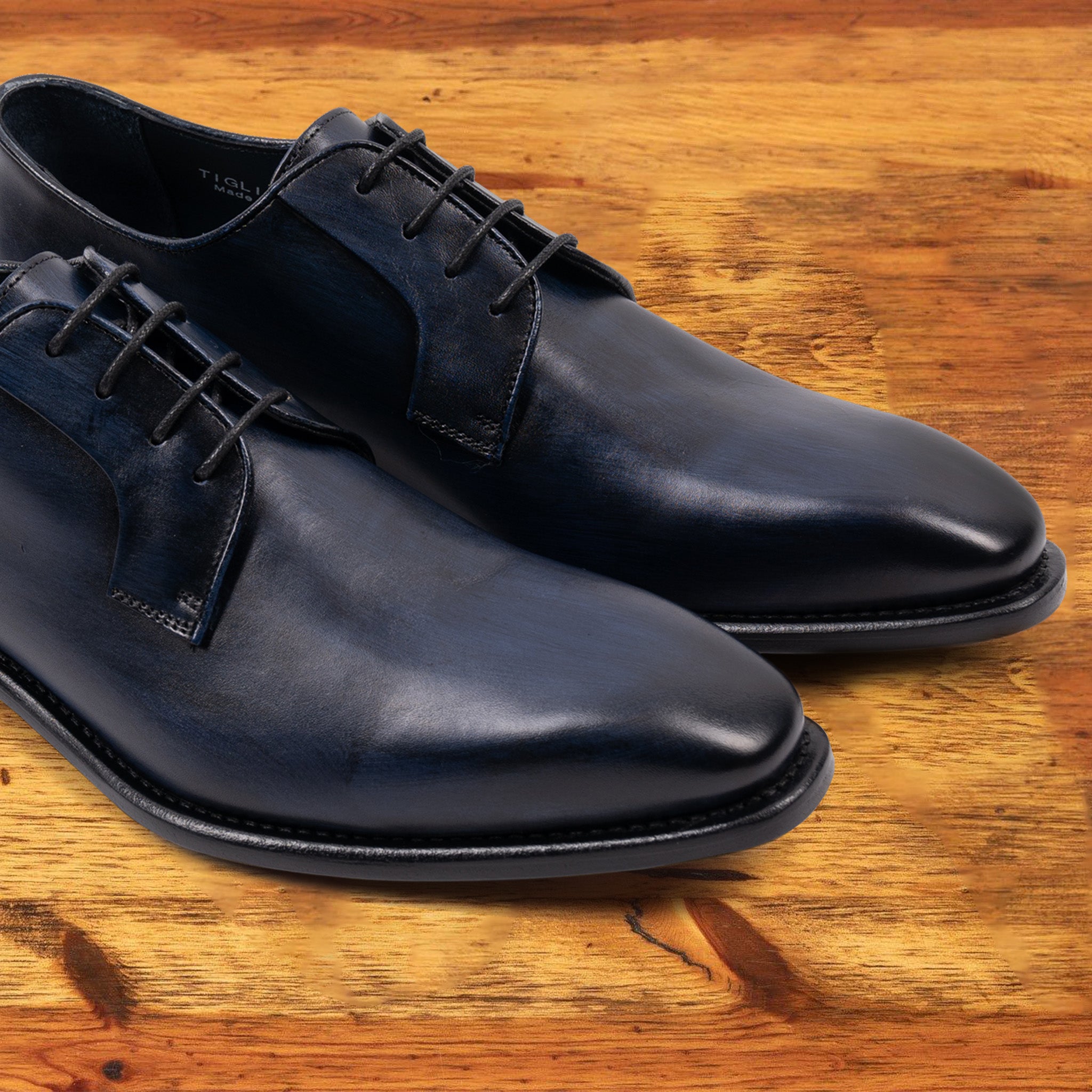 A Pair of Blue leather dress shoe on a wooden surface