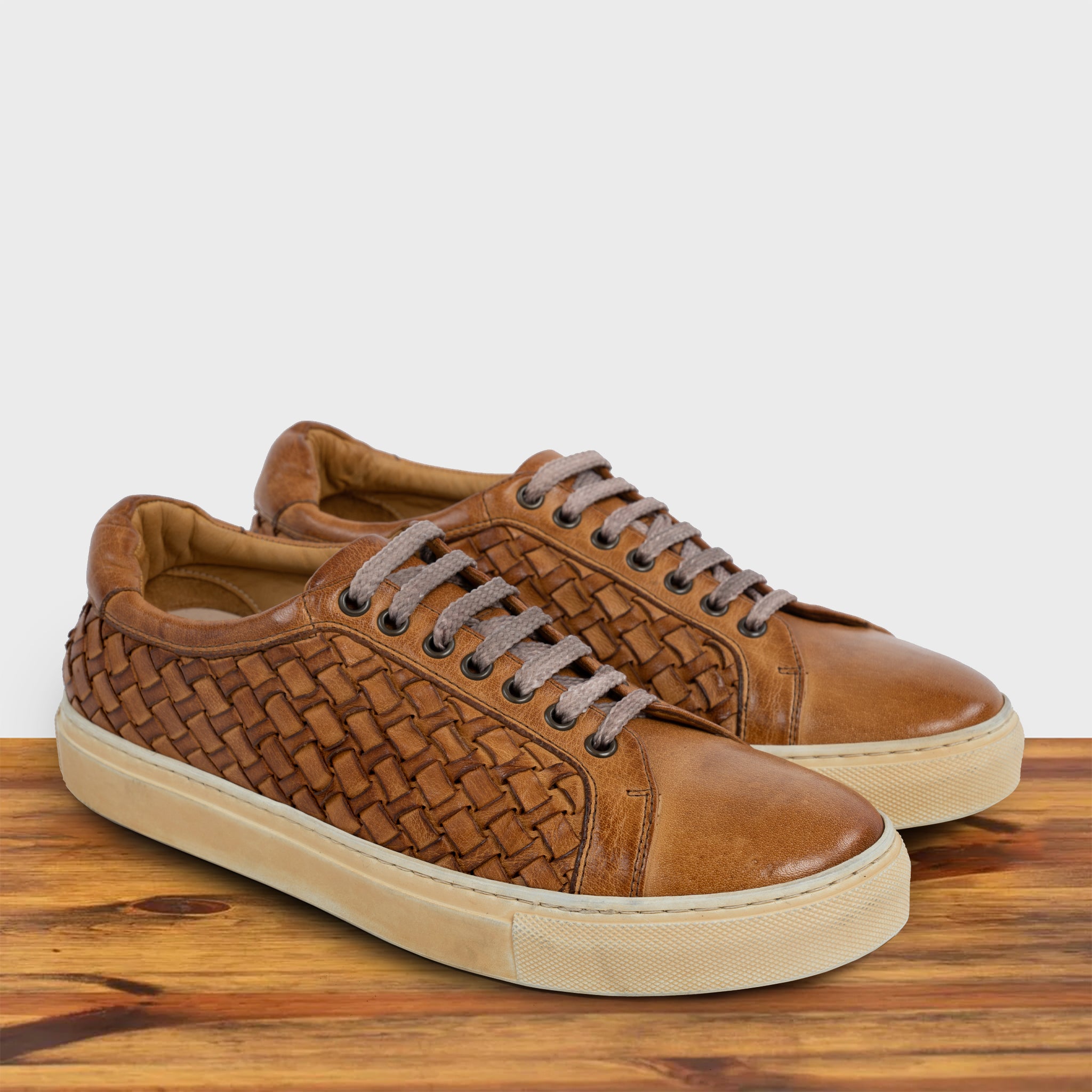 A Pair of Brick woven sneaker on a wooden surface with a light gray background