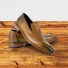 A Pair of Spice leather loafer on a wooden surface with a light gray background