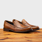 Pair of Brown leather loafer on a wooden surface with a light gray background