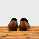 Back Side of Brown leather loafer on a wooden surface with a light gray background