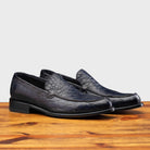 A Pair of Blue leather loafer on a wooden surface with a light gray background