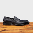 Blue leather loafer on a wooden surface with a light gray background