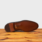 Outsole of Blue leather loafer on a wooden surface with a light gray background