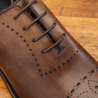 Brown leather dress shoe on a wooden surface