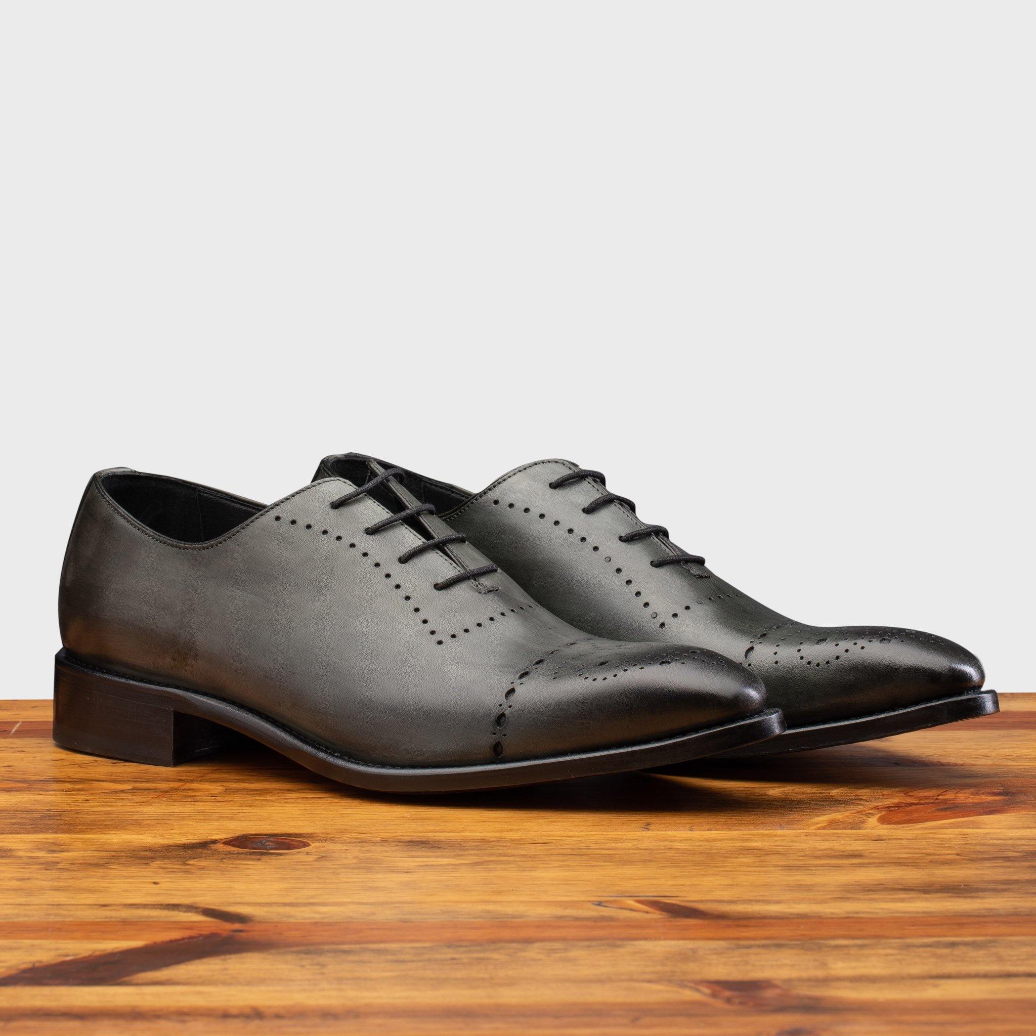 A Pair of Emerald leather dress shoe on a wooden surface with a light gray background