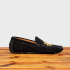 Black loafer with gold embroidery on a wooden surface