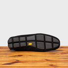 Outsole of Black loafer with gold embroidery on a wooden surface