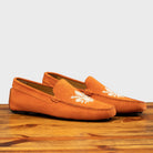 A Pair of Papaya loafer with embroidery on a wooden surface